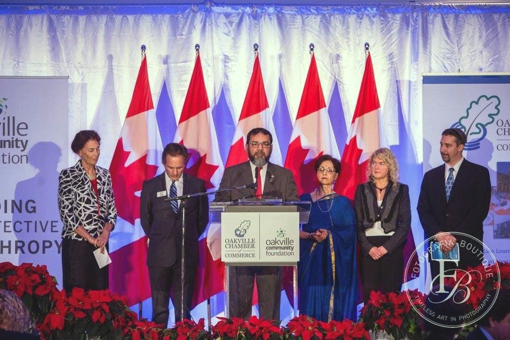 Council leaders on stage at the Oakville Chamber of Commerce programme, December 2015, with Imam Abdul-Qayyum Mufti at the podium.